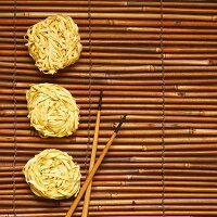 Chinesische Eiernudeln und Essstäbchen auf Bambusmatte