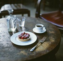 Himbeertörtchen, eine Tasse Kaffee und ein Glas Wasser