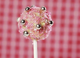 A cake pop, chilled and decorated with light chocolate and sugar strands