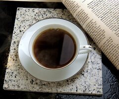 Eine Tasse schwarzer Kaffee mit einer Zeitung