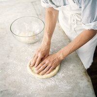 Flattening pizza base by hand