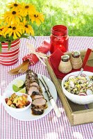 Gebratenes Schweinefilet mit Salat auf sommerlichem Tisch