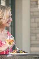 Blond woman at table with salad and wine