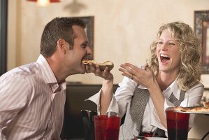 Woman feeding man pizza in restaurant