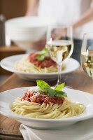 Spaghetti mit Tomatensauce und Weissweingläser auf Tisch