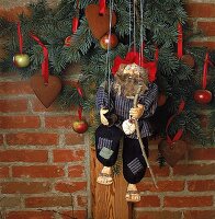 Marionette hängt vor weihnachtlich dekorierter Mauer