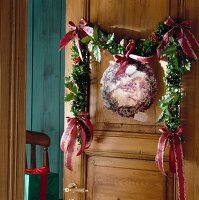Holly berry leaves garland with picture of Santa Claus hanging on wooden door