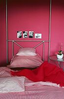 Aluminiumbett, rosa Tapete und Bettwäsche, rote Decke auf dem Bett