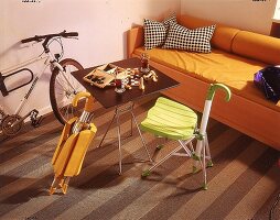 Klappmöbel: grüner und oranger Stuhl mit Regenschirmgriff und Tisch