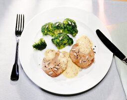 Veal steak with broccoli on plate with knife and fork