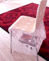 Stuhl mit transparenter Husse und roter Wollteppich