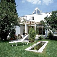 Verglaster Anbau eines  weissen Einfamilienhauses mit Terrasse u. Garten