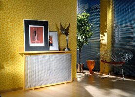 Radiator concealed by metal mesh encased in wooden frame on yellow wall