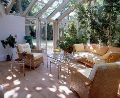 Seaweed sofa, cotto tiles and green plants in open room with glass doors