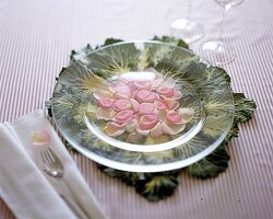 Rosenblätter auf einem Glasteller, ein Kohlblatt als Platzset.