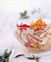 Penne, chicken, chilli cream, yellow and red pepper in glass bowl