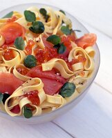 Tagliatelle with salmon and watercress in glass bowl on table