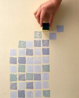 Mit einem kleinen Stempel werden Quadrate auf eine Wand gedruckt