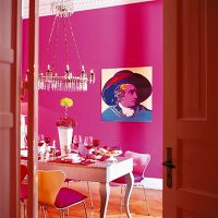 Dining area with pink wall, dining table and chandelier