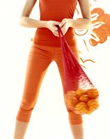 Frau schwingt ein Netz mit Orangen, nur ihre Beine sichtbar