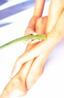 Nude woman sitting and holding aloe leaf in hand looking down and smiling