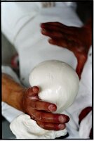 Mozzarella-Herstellung; eine große Kugel wird mit den Händen geformt