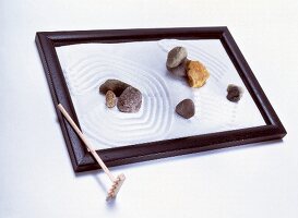 geharkter Zen-Garten mit Harke und acht Steinen