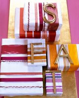 Geschenkverpackungen: farblich abge- stimmte Bänder und Buchstaben