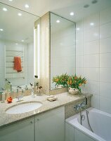 Granite countertop, mirror and bathtub in modern bathroom
