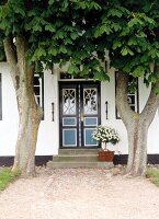 Two chestnut trees in front of thatched house door in Westerland, Sylt, Germany