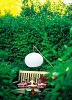 Abendessen im grünem Garten: kleiner gedeckter Tisch mit Kerzen, Lampion