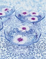 schwimmende rosa Blüten in Glasschalen auf blauer Blütentischdecke