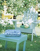 Gartenstuhl aus weiß lackiertem Holz mit Fußhocker im Garten, Apfelbaum