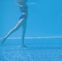 Frau im Pool bei Oberschenkelübung, Unterwasseraufnahme