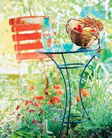 Blue round iron table with basket, glass vase and cup in garden