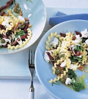 Fusilli mit Spinat, getrockneten Tomaten + Ricotta auf blauen Tellern