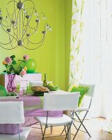 Green wall, chandelier and pink-white dining table in dining room