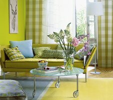 Grünes Sofa, runder Glastisch, Vase mit Blumen
