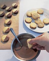 Plätzchen die mit Kuvertüre überzogen werden auf Backpapier trocknen