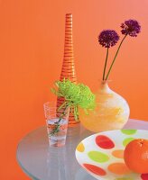 Still mit Vasen und bunter Schale, Blumen, Hintergrund orange