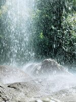 Wasser eines Wasserfalls prasselt auf Felsbrocken, auf Steine