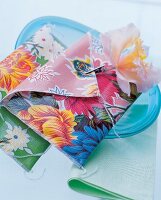 Two floral pattern napkin bags made of oilcloth with artificial flower to pin