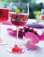Sparkling wine with raspberry syrup and mint leaf in wine glass