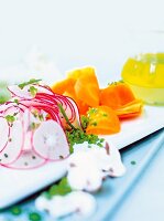 Slices of carpaccio, carrot and radish on chopping board