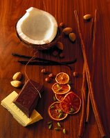 Coconut, vanilla, cinnamon, chocolate, orange slices, nuts and cloves on wooden surface