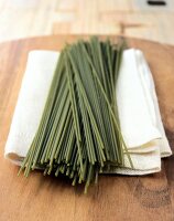 Raw spinach spaghetti on a white towel on wooden table