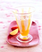 Soy and peach shake in a glass with straw on tray