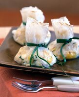 Close-up of sprossen mix in rice paper bags on brown plate with forks