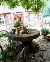 Mühlrad im Garten dient als Tisch um Blumen ein- und umzutopfen