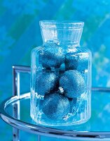 Bonbonniere aus geriffeltem Glas mit blauen Weihnachtskugel gefüllt